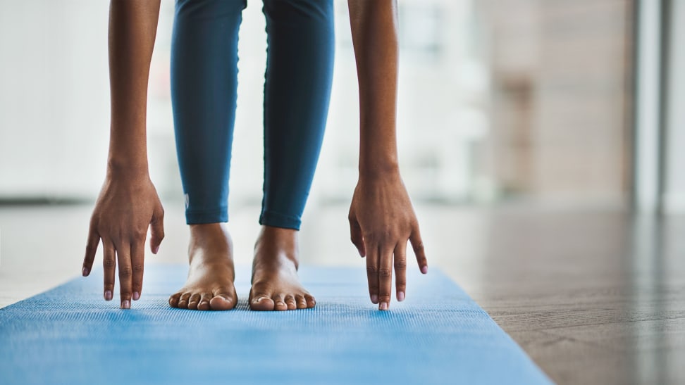 A woman touching her toes on a yoga mat.