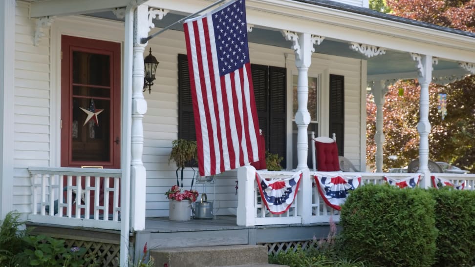 White house with patriotic decor on porch.