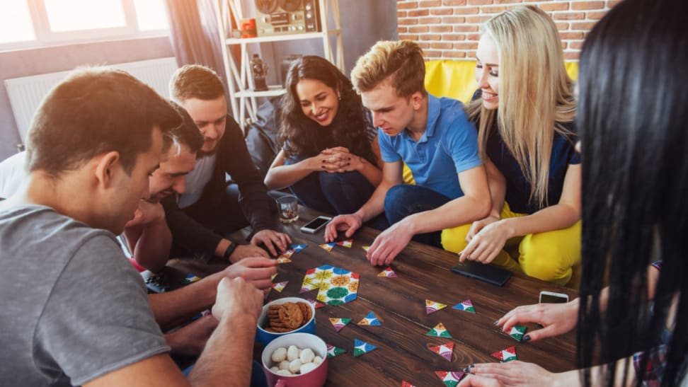 Adults sitting around table playing board game