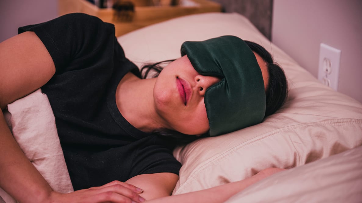 Person wearing silk sleep mask laying in bed
