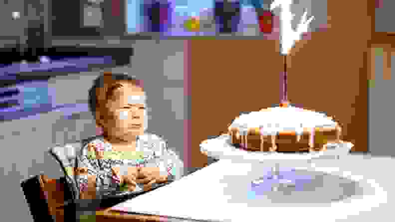 A baby looks scared as her 1st birthday candles goes up in a flare.