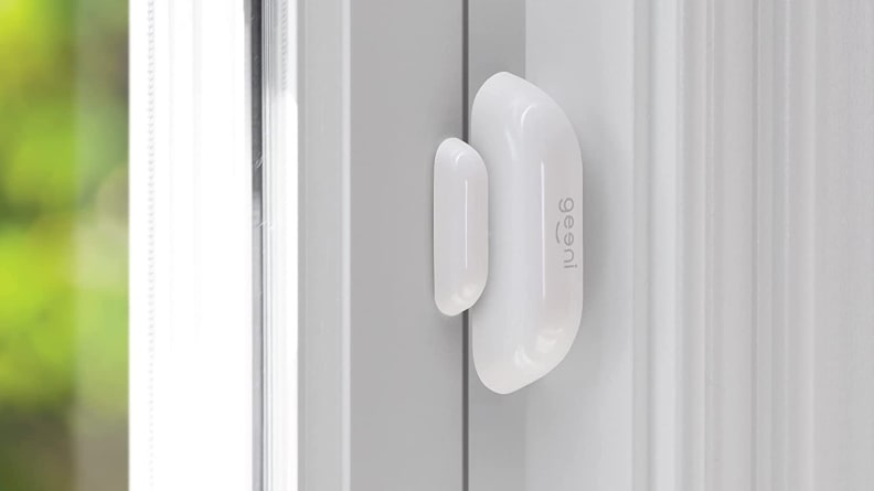 White oval smart sensor mounted on white door.