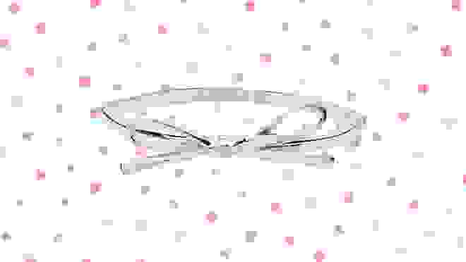Silver bracelet against a white background with pink polka dots