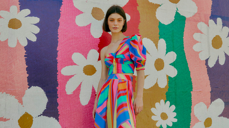 A model poses against a floral backdrop.