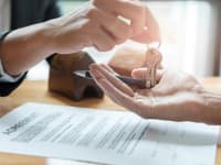 A person handing over a set of keys over a contract