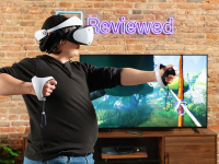 A person wearing a white PSVR 2 headset mimicking pulling back a bow and arrow in front of a TV