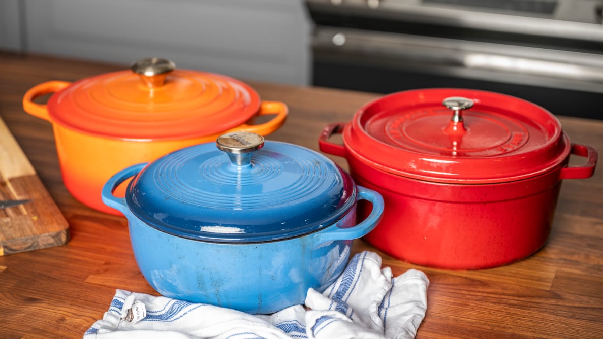 Three colorful Dutch ovens sit on a kitchen counter.