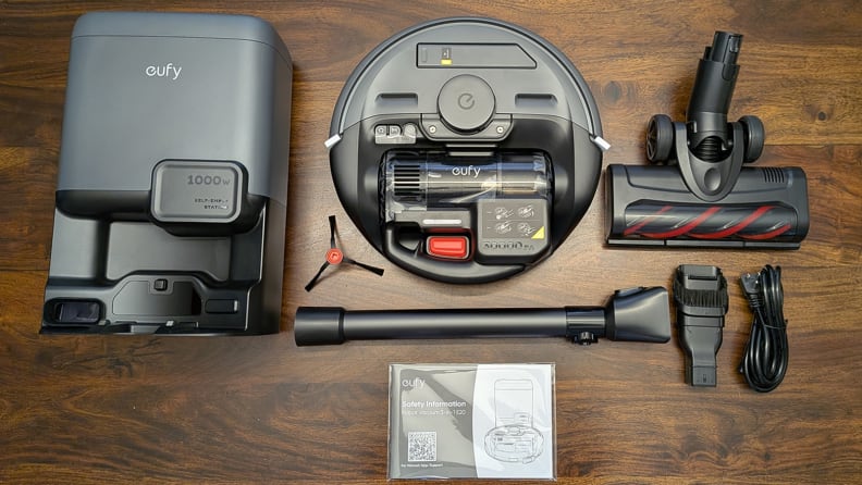 A black robot vacuum plus attachments on a wood floor