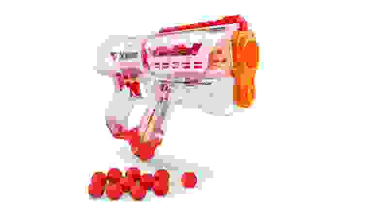 Plastic, clear Nerf gun next to red balls.