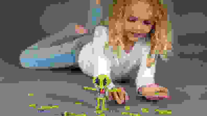 little girl building an alien out of PlusPlus blocks
