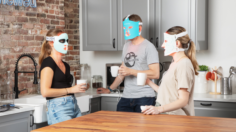 Three people standing in a kitchen drinking coffee.