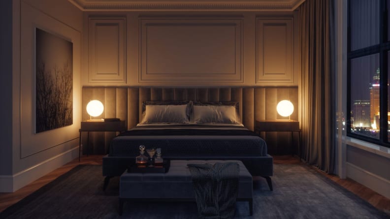A dark hotel room with two bedside lamps illuminating the headboard.