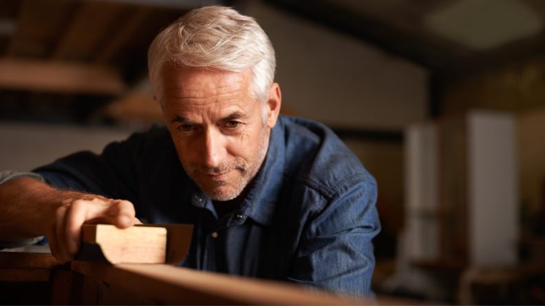 A person examines a piece of wood to stain.