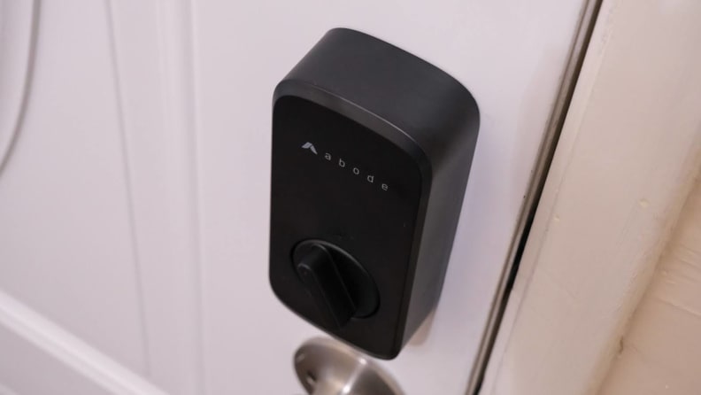 The Abode Lock mounted on white door above door handle.