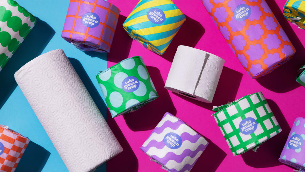 Colorful rolls of toilet paper and paper towels on blue and pink background