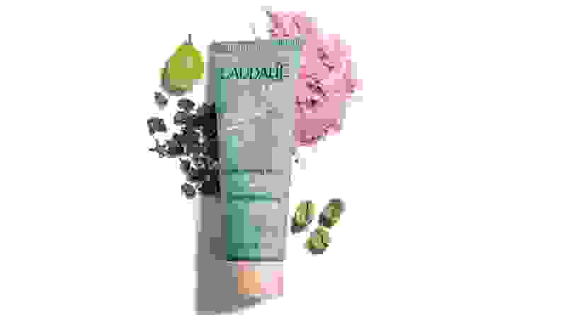 A picture of Caudalie detox mask surrounded by fruits and herbs.
