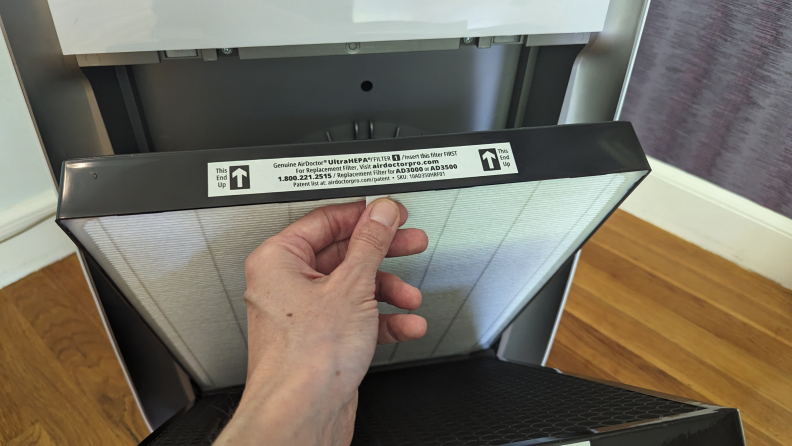 A hand holds the tab on the front of the Air Doctor Pro 3500i’s UltraHEPA filter, which demonstrated some of the best air purifier performance we’ve seen.