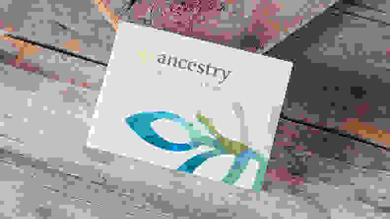 An AncestryDNA kit against a wood background, among the best 30th birthday gift ideas.