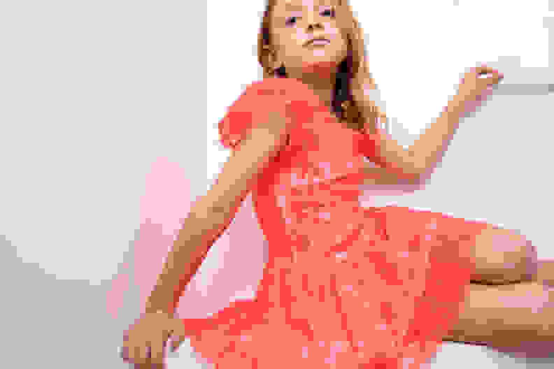 A girl wearing a bright pink lace dress.