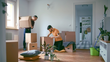 Two people packing up boxes in an mostly empty room.