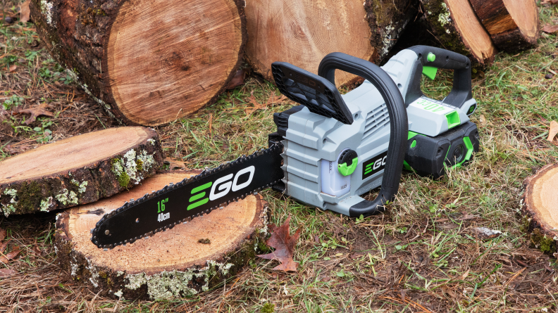 An Ego Power chainsaw appears next to a log.