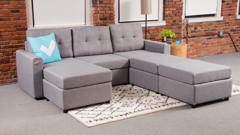 A gray upholstered couch with the ottomans arranged on one side to create a long chaise.