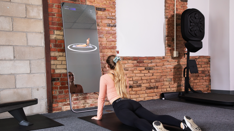 A woman in cobra pose in front of the Fiture workout mirror.
