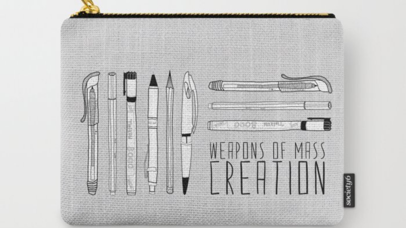 Gray pouch with gold zipper that has pens, pencils and markers printed on front. Carry all pouch also reads, "Weapons of mass creation."