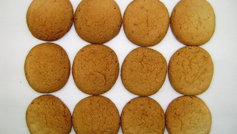 Three rows of sugar cookies with uneven baking—darker in the middle and lighter on the edges