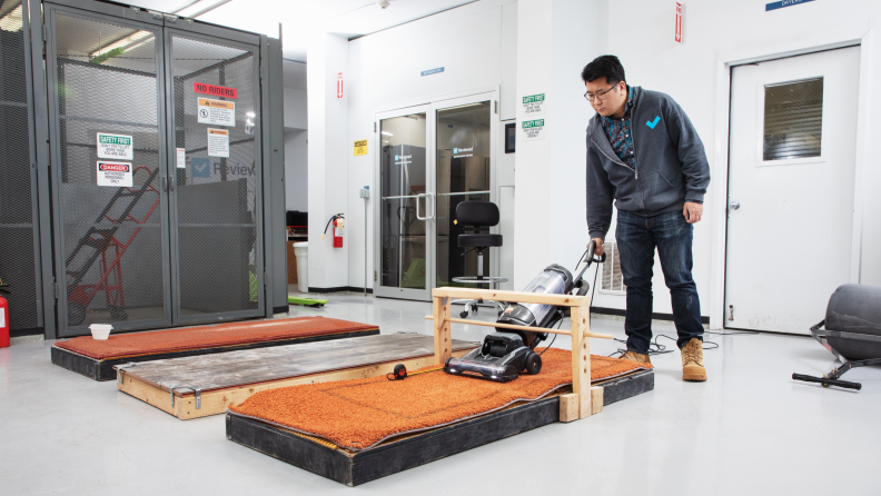 A person in a lab vacuuming a carpeted surface as part of testing the best vacuums
