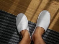 Man wearing a pair of white slippers.