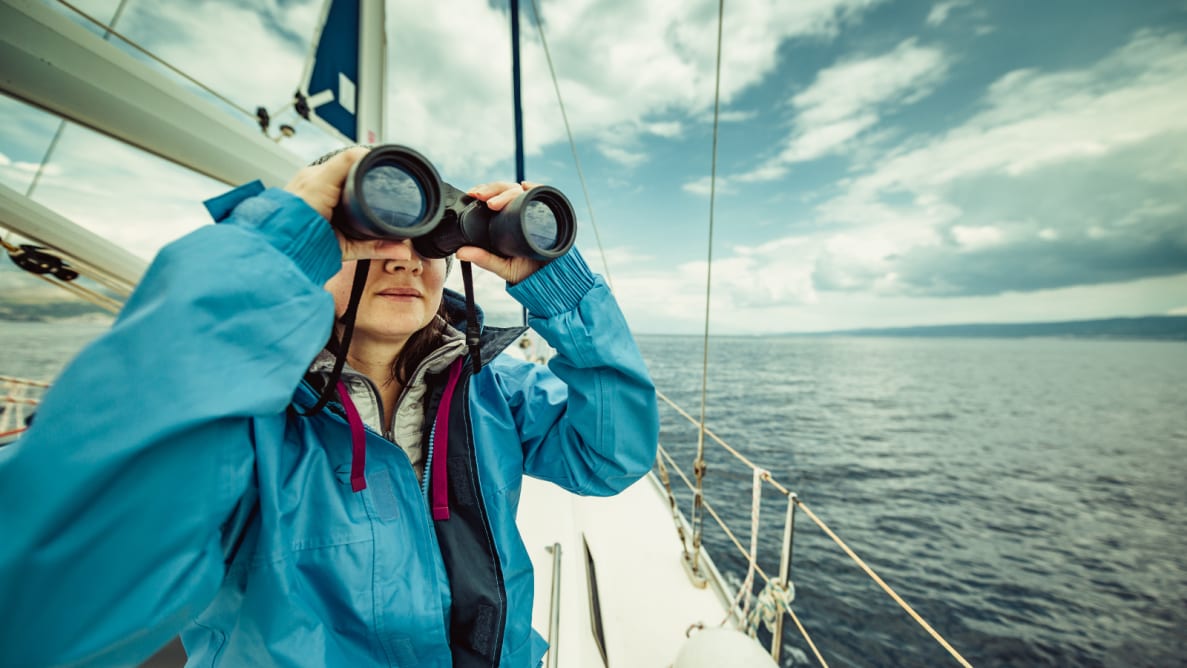 女孩在船上用双筒望远镜。