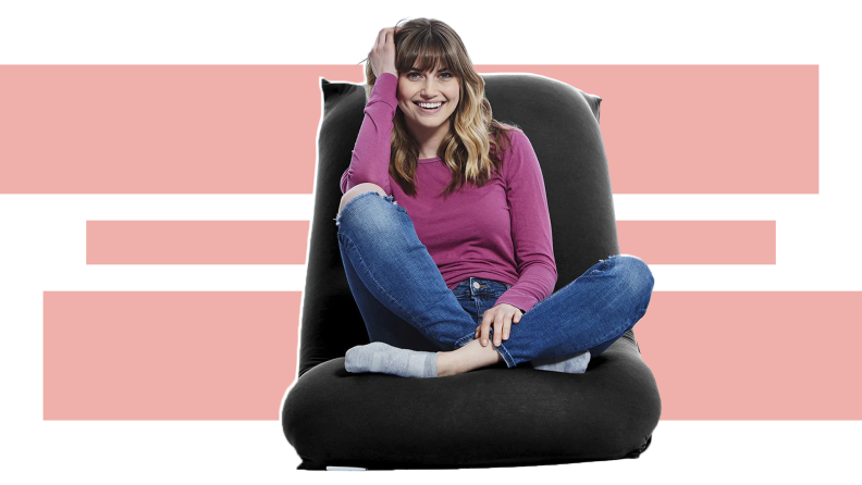 A smiling person lounges on a black Yogibo Lounger.
