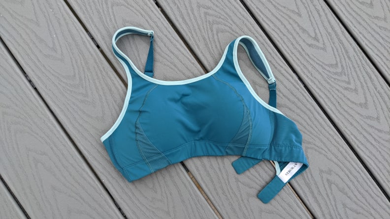 A teal blue sports bra on a gray plank background.