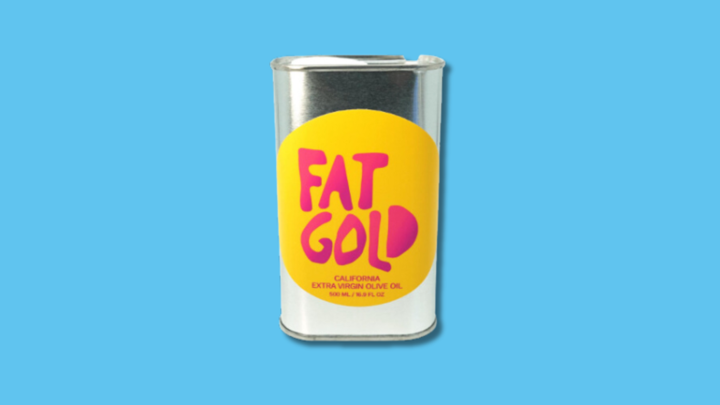 Silver tin with yellow and red label for Fat Gold Olive Oil in front of blue background.