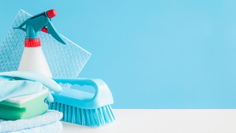 Different types of cleaning product gathered together in front of blue background.