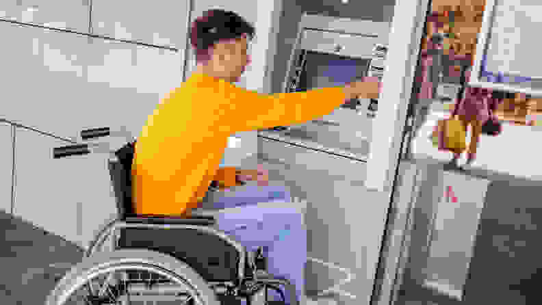 A person in a wheelchair using an ATM.