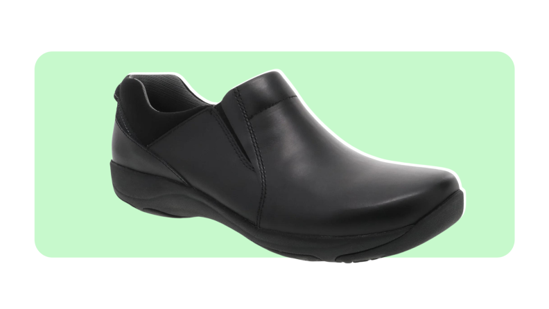 A black leather clog featured on a green and white background