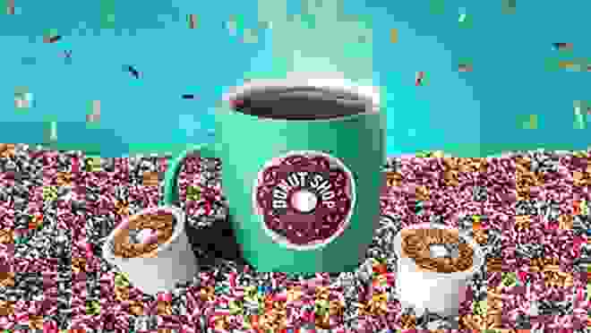 A coffee mug with Keurig's Donut Shop logo on it, with a K-cup on each side.