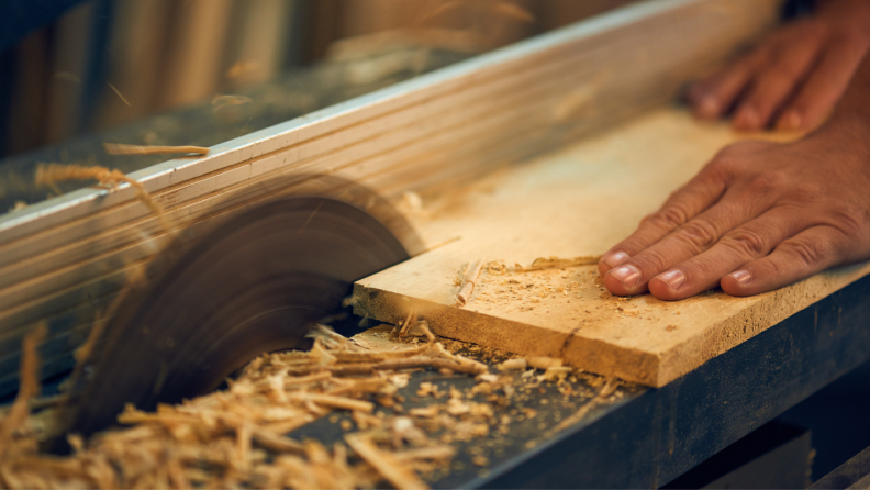 Man using table saw to cut 2x6 board.