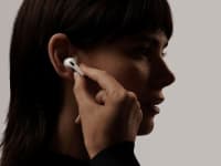 A person puts an AirPod into their ear.
