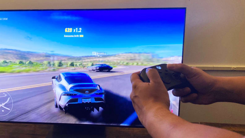 Zbliżenie dłoni osoby trzymającej konsolę Xbox Series X podczas grania w Forza Horizon 5 przez Samsung Gaming Hub