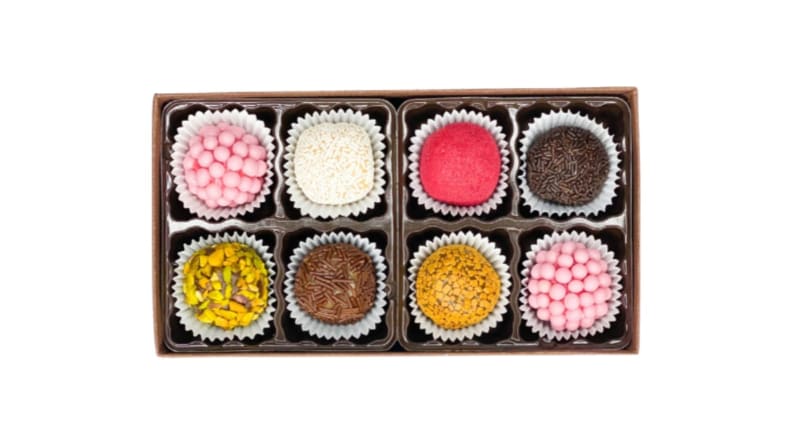Una caja de ocho chocolates brasileños multicolores cubiertos con rellenos amarillos, rosas, marrones y blancos.