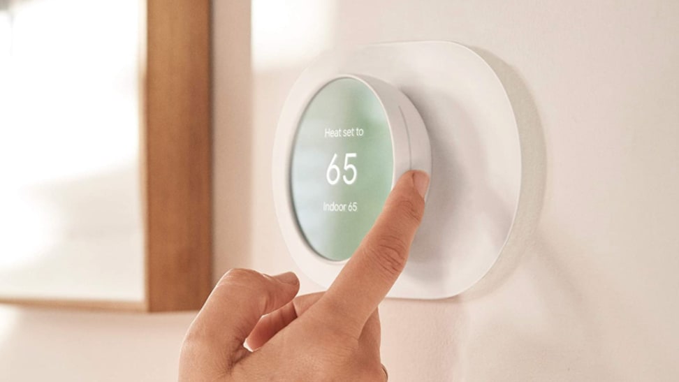 Person adjusting a smart thermostat on the wall.