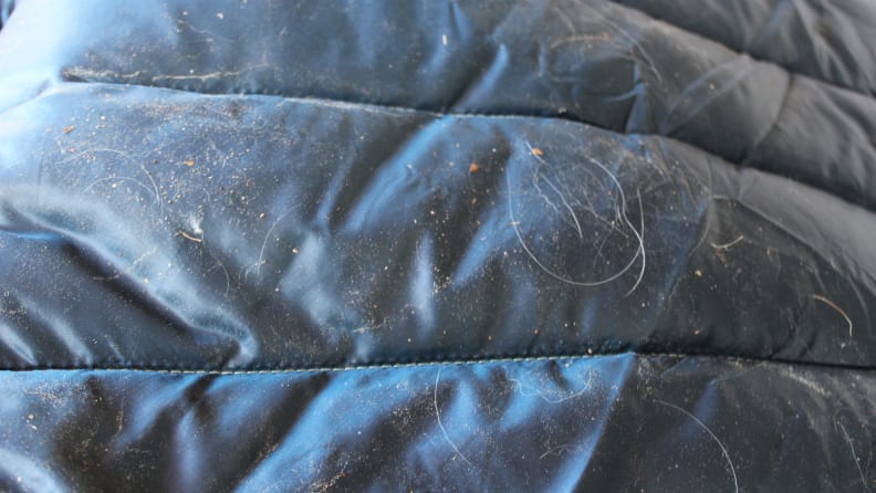 Navy blue nsulated puffy blanket with pet hair and debris attached to it.