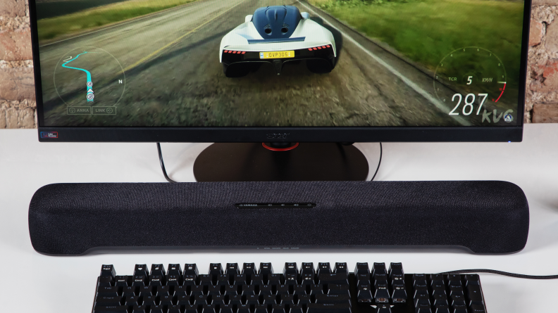 The Yamaha SR-C30A on a white desk with a keyboard and monitor displaying a racing game.