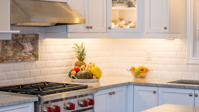 A kitchen is lit by cabinet lighting.