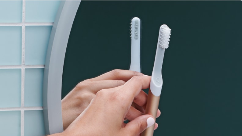 The Quip electric toothbrush being placed in its wall-mounted holder