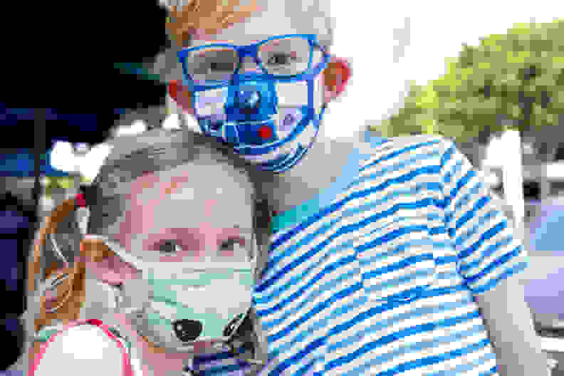 A young girl and young boy wearing face masks with an image of Baby Yoda and R2D2