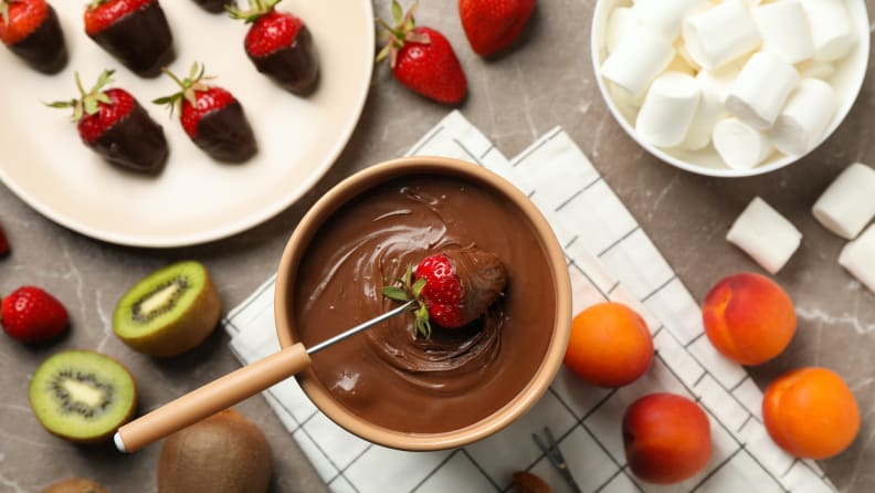 Composition with ingredients for chocolate fondue on gray table.